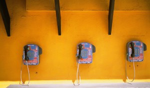 Three payphones on a yellow wall